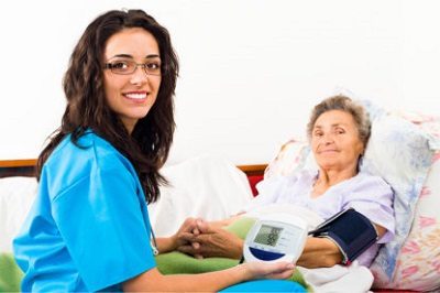 A woman sitting next to an older person in bed.